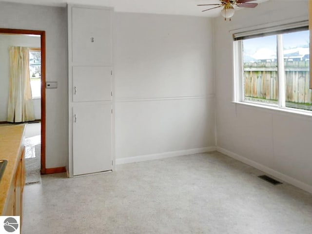 empty room with visible vents, baseboards, ceiling fan, and light carpet