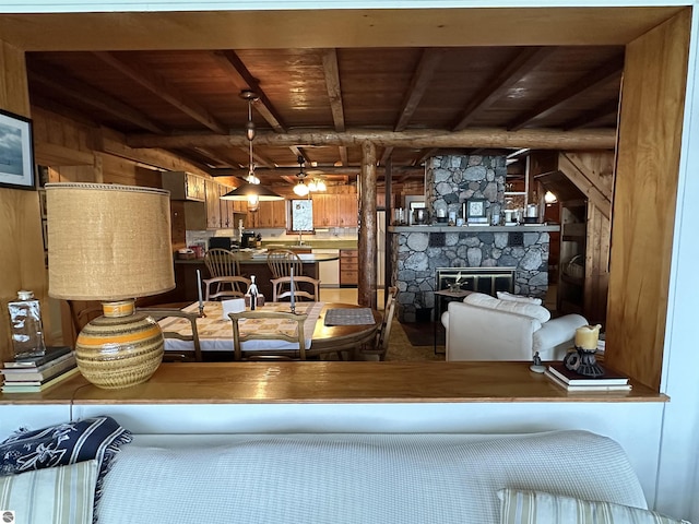 living room featuring wood walls, wood ceiling, beam ceiling, and a fireplace