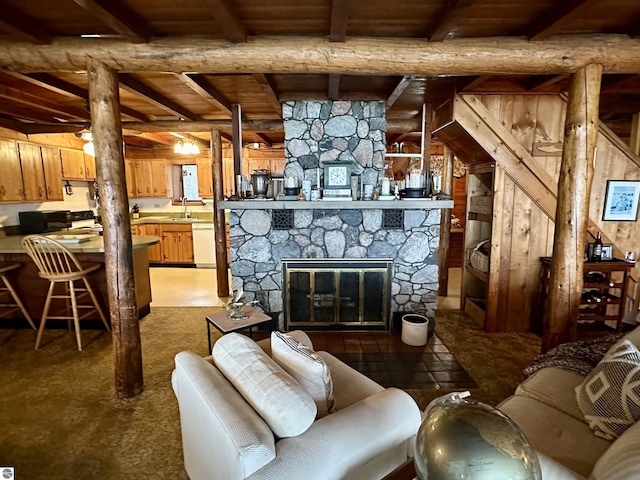 living area featuring a stone fireplace, wood ceiling, and beam ceiling