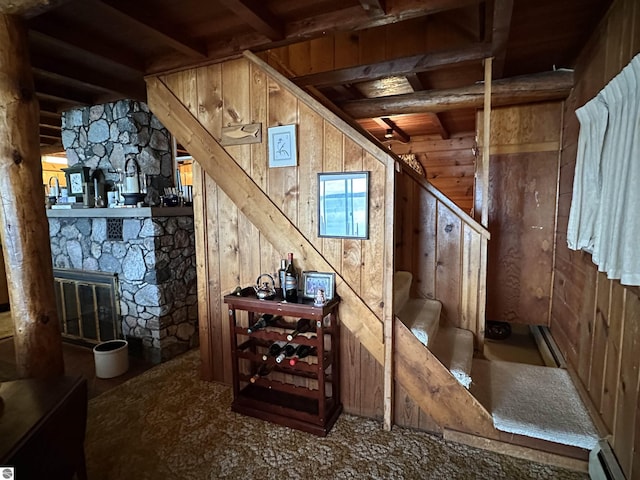 wine cellar with wood ceiling, a baseboard radiator, a fireplace, and wood walls