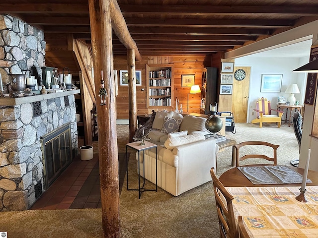 living area featuring carpet flooring, wood walls, beam ceiling, and a fireplace