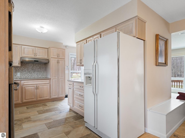 kitchen with plenty of natural light, a textured ceiling, under cabinet range hood, and white fridge with ice dispenser