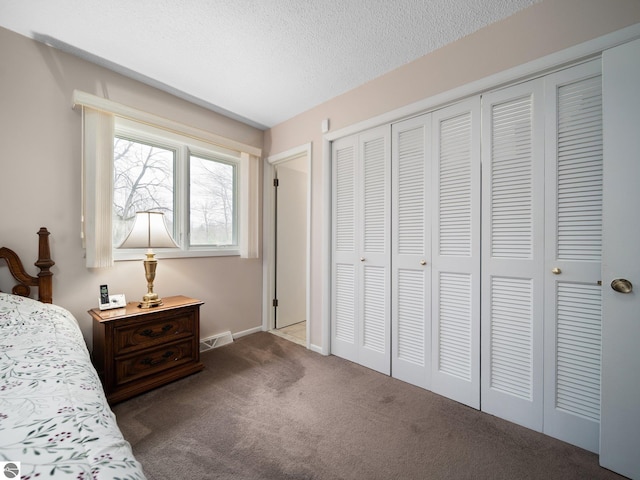 carpeted bedroom with baseboards, a closet, a textured ceiling, and visible vents