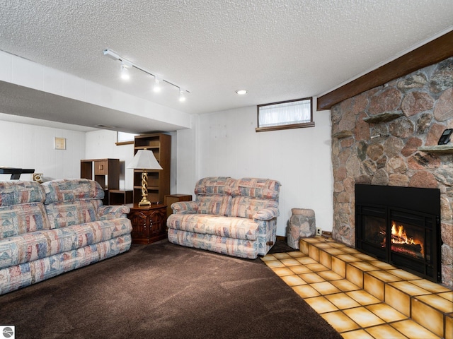 living room with a textured ceiling, track lighting, and a fireplace