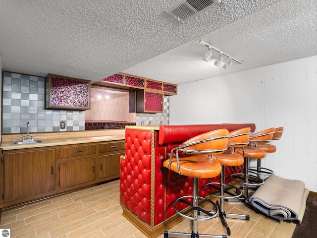 bar featuring visible vents, wood tiled floor, rail lighting, a sink, and a dry bar