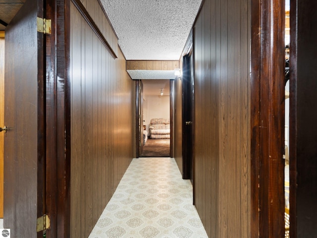 hallway with wooden walls and a textured ceiling