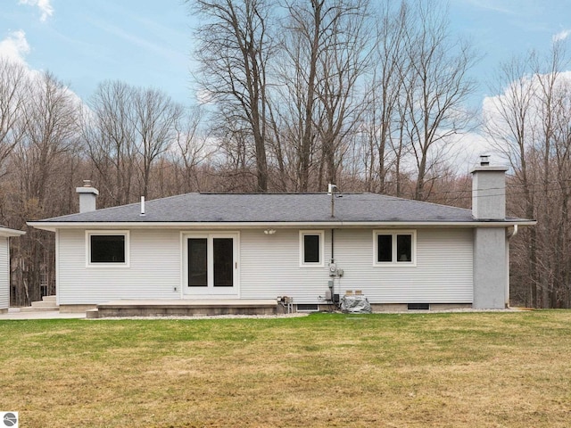 rear view of house with roof with shingles, a yard, and a chimney