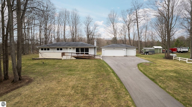 view of front of house featuring a chimney, a deck, a detached garage, an outdoor structure, and a front lawn