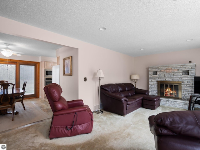 living room with a textured ceiling, a glass covered fireplace, and light carpet