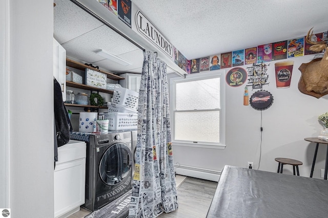 laundry room with light wood-type flooring, a textured ceiling, cabinet space, and a baseboard heating unit