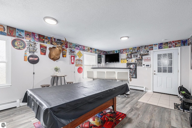rec room with light wood-style floors, pool table, a baseboard heating unit, and a textured ceiling