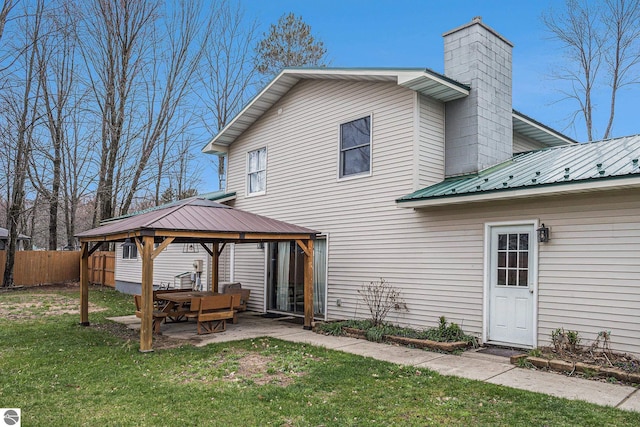 back of property with fence, a patio area, metal roof, a gazebo, and a yard