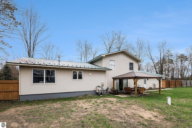 back of house featuring fence, a patio area, metal roof, a gazebo, and a yard