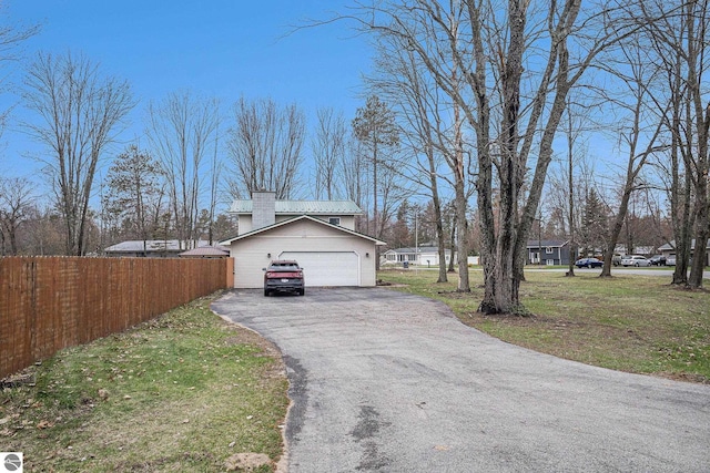 view of home's exterior featuring a yard, fence, a chimney, and aphalt driveway