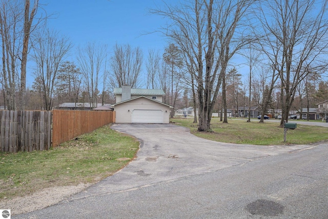 exterior space featuring fence, a front lawn, and aphalt driveway