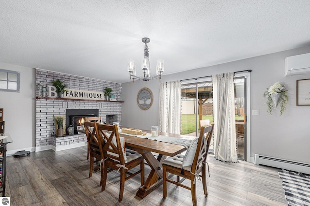 dining area with baseboard heating, a brick fireplace, a textured ceiling, a wall unit AC, and wood finished floors
