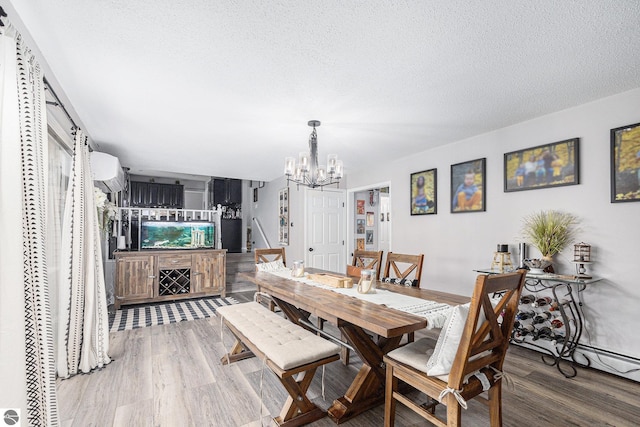 dining room featuring a textured ceiling, a wall unit AC, wood finished floors, and a notable chandelier