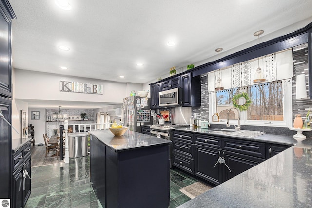 kitchen with dark cabinets, appliances with stainless steel finishes, backsplash, and a kitchen island