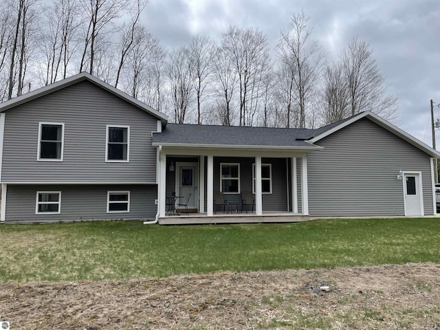 split level home with a porch, a shingled roof, and a front yard