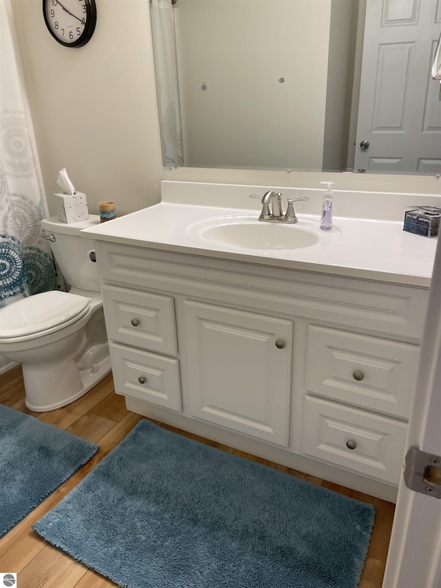 full bath with toilet, wood finished floors, and vanity