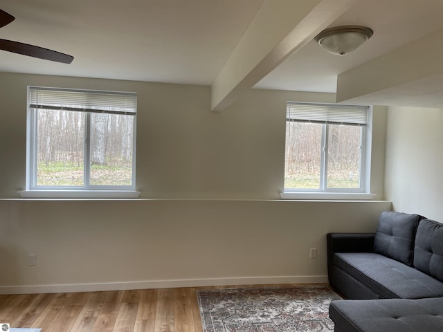 living area featuring baseboards, ceiling fan, and wood finished floors