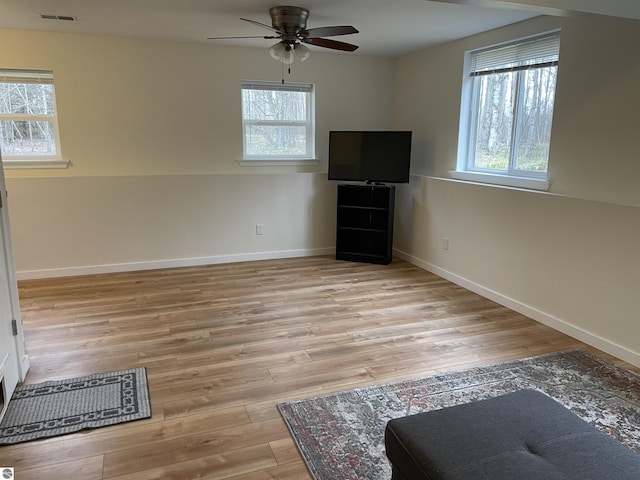 unfurnished living room featuring a ceiling fan, visible vents, plenty of natural light, and light wood finished floors
