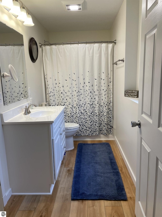 full bath featuring vanity, toilet, wood finished floors, and visible vents
