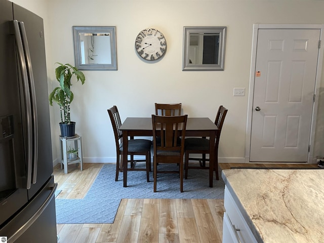 dining room with baseboards and light wood-type flooring