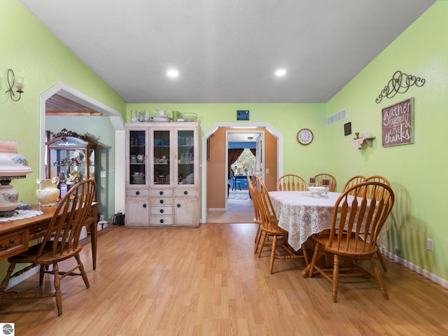 dining room with arched walkways, light wood-style flooring, and visible vents