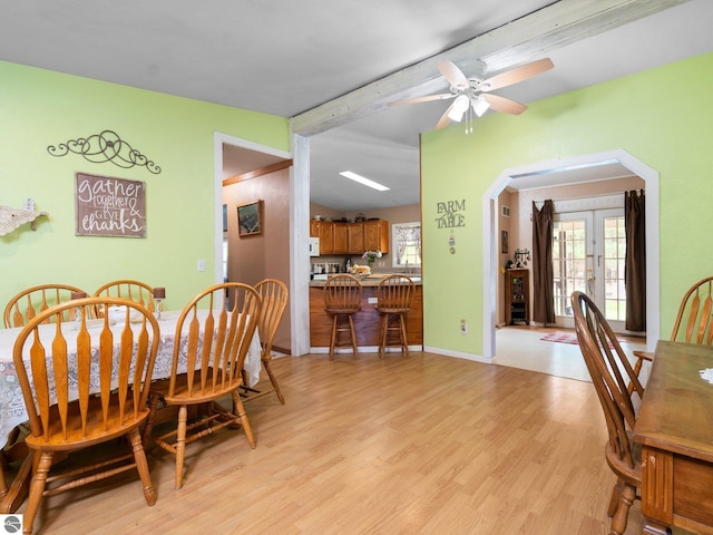 dining area featuring arched walkways, ceiling fan, lofted ceiling with beams, and light wood-type flooring