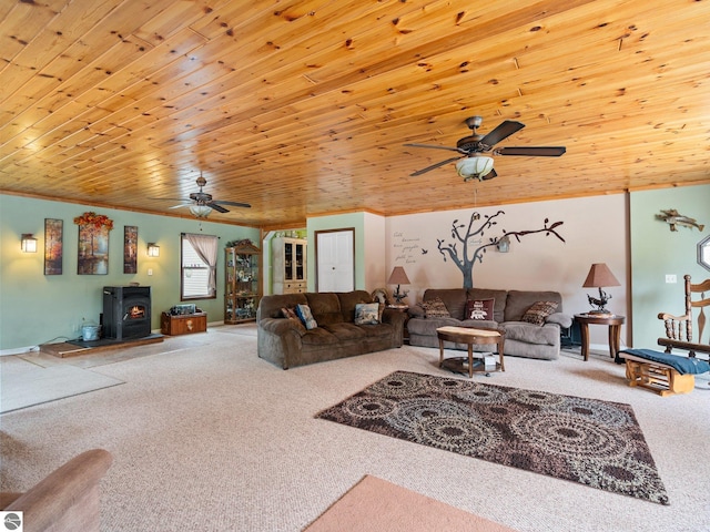 carpeted living room featuring crown molding, wooden ceiling, ceiling fan, and a wood stove