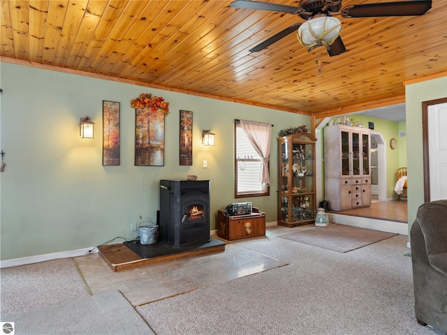 living area featuring wooden ceiling, baseboards, a ceiling fan, and a wood stove
