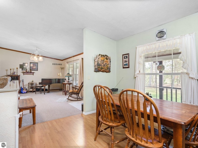 dining room featuring crown molding, light wood finished floors, a chandelier, baseboards, and visible vents