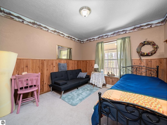 carpeted bedroom featuring a wainscoted wall, wood walls, and a textured ceiling