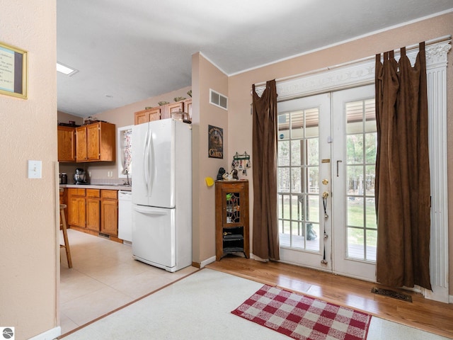kitchen with visible vents, light countertops, brown cabinetry, and white appliances