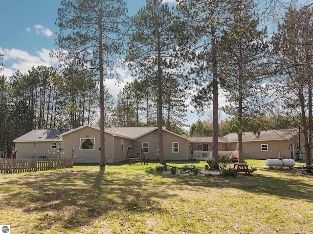 rear view of house with a lawn and fence