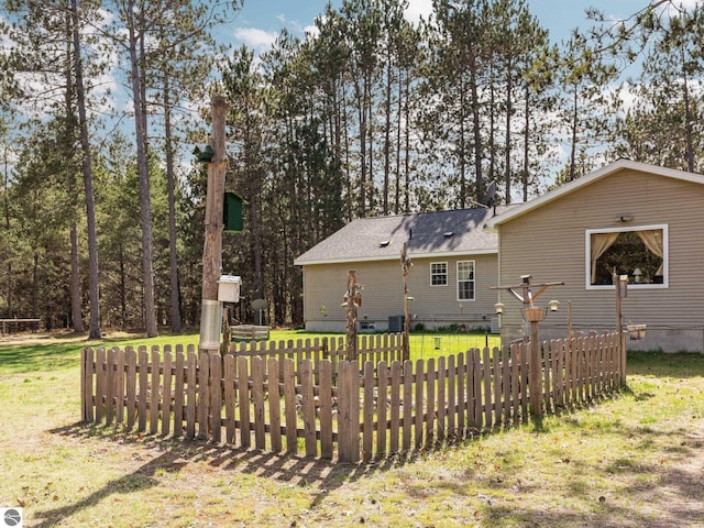 rear view of property featuring fence, a yard, roof with shingles, and crawl space