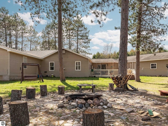 back of property with a fire pit, a yard, and a deck