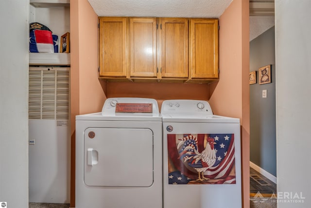 clothes washing area featuring baseboards, a heating unit, cabinet space, and washer and dryer