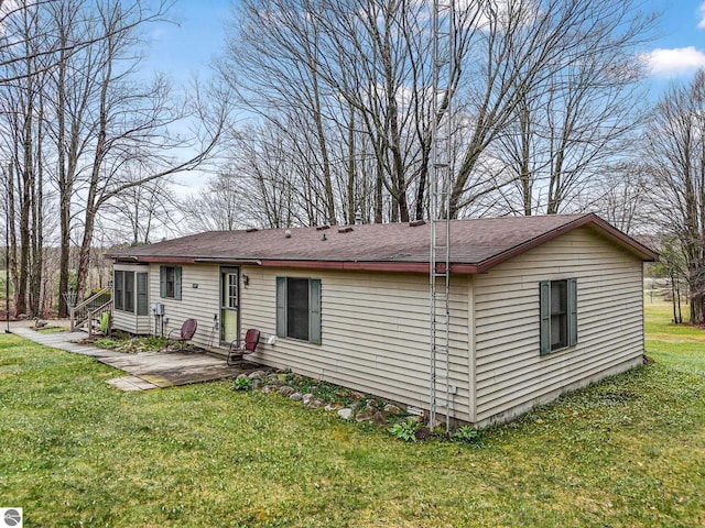 back of property with a patio, a shingled roof, and a yard
