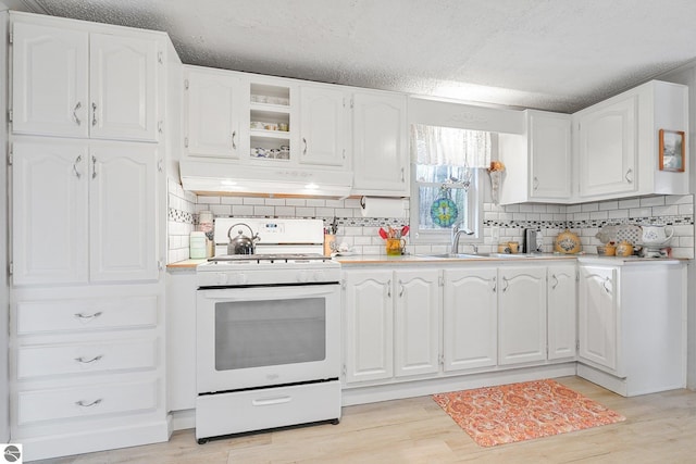 kitchen featuring decorative backsplash, under cabinet range hood, white range with gas cooktop, and white cabinetry
