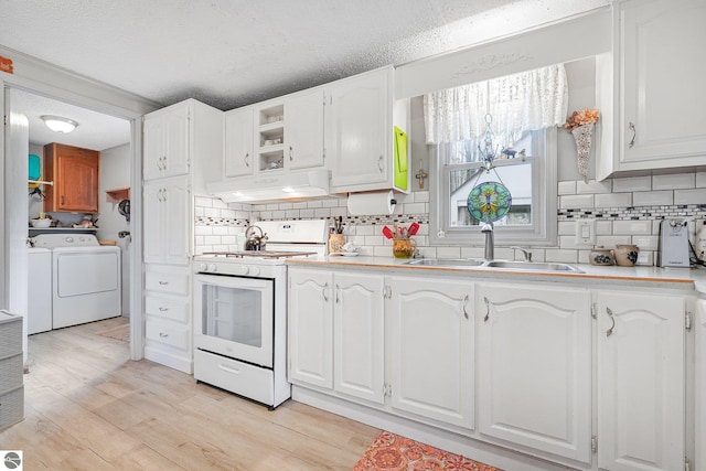 kitchen featuring under cabinet range hood, backsplash, white gas stove, and washer and clothes dryer