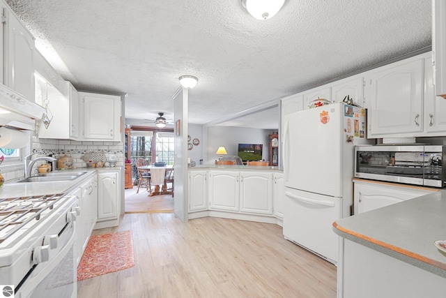 kitchen featuring white appliances, a textured ceiling, a sink, and light wood-style floors