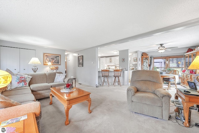carpeted living area featuring a textured ceiling and ceiling fan