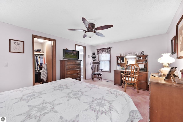 bedroom with a walk in closet, a ceiling fan, a closet, and light colored carpet