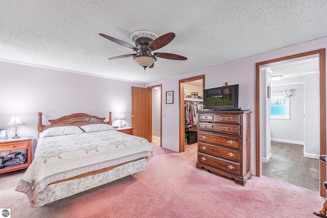 bedroom with carpet, a ceiling fan, baseboards, a spacious closet, and a closet