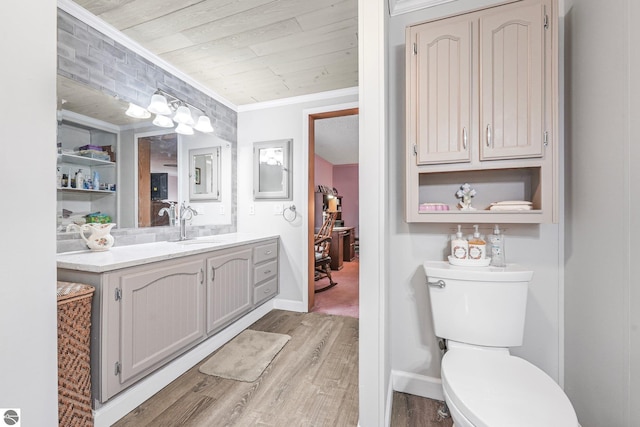 bathroom with vanity, crown molding, wood finished floors, and toilet