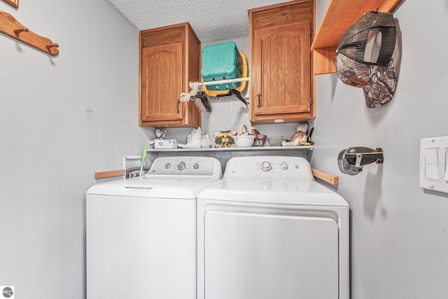 laundry room with a textured ceiling, cabinet space, and washing machine and dryer