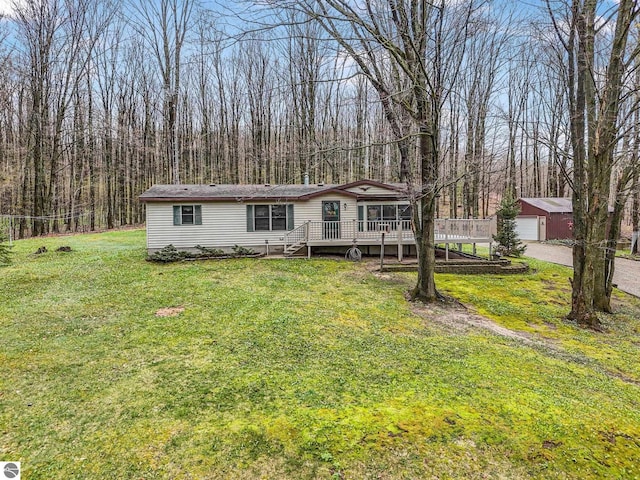 manufactured / mobile home featuring a detached garage, a deck, a front yard, an outdoor structure, and driveway
