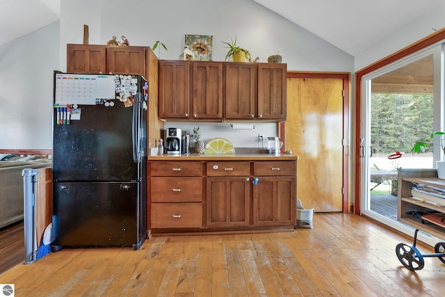 7276 Tiger Dr Unit A, And B, Lake Ann, MI 49650 - kitchen with light wood-type flooring, freestanding refrigerator, brown cabinetry, and lofted ceiling
